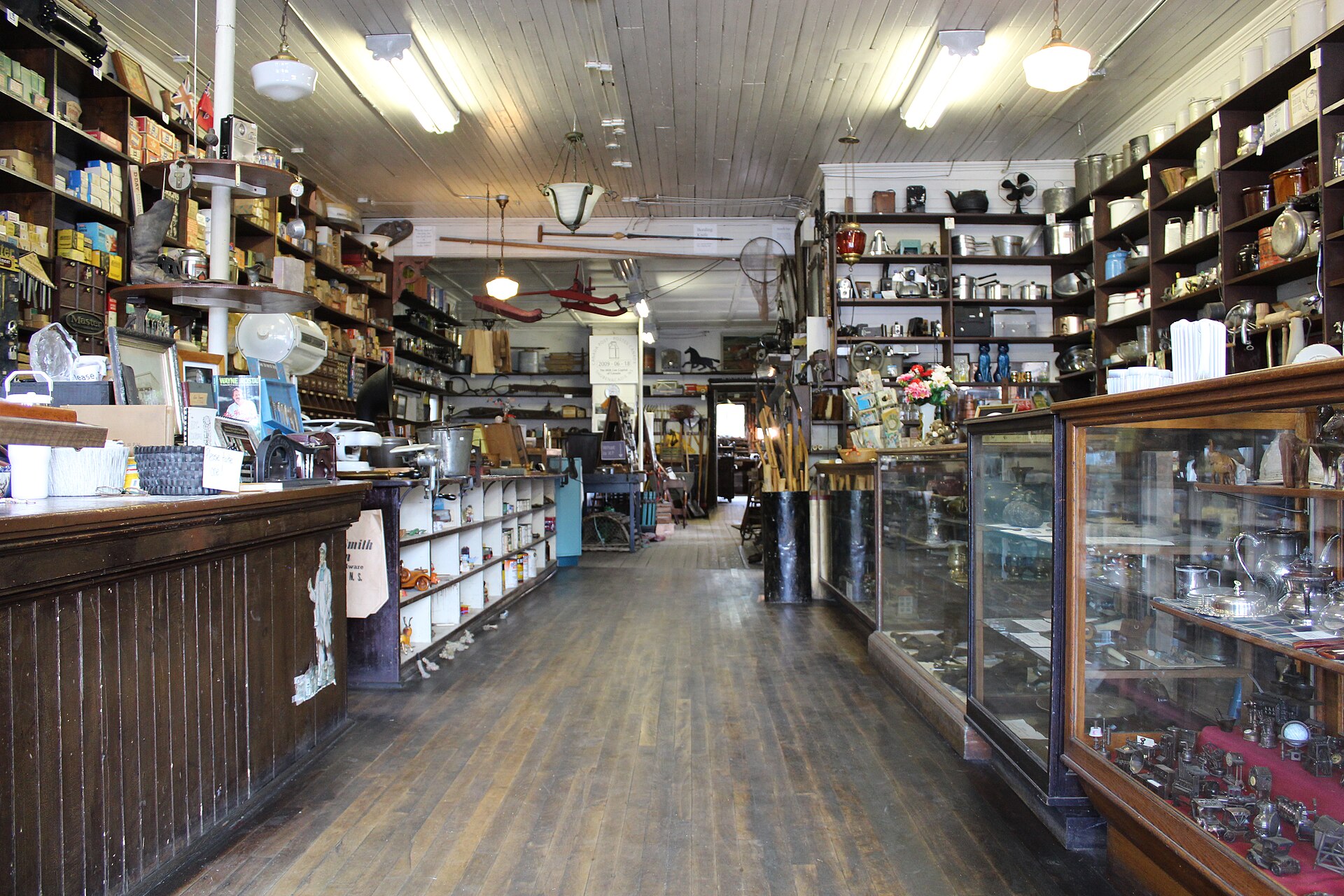 Inside an old hardware store: wooden counters, glass display cases and shelves of tools and tins.